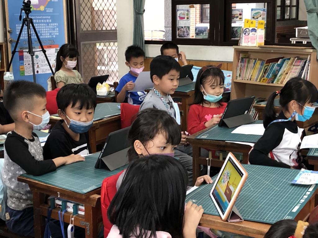 A group of children sitting at desks with laptopsDescription automatically generated with medium confidence